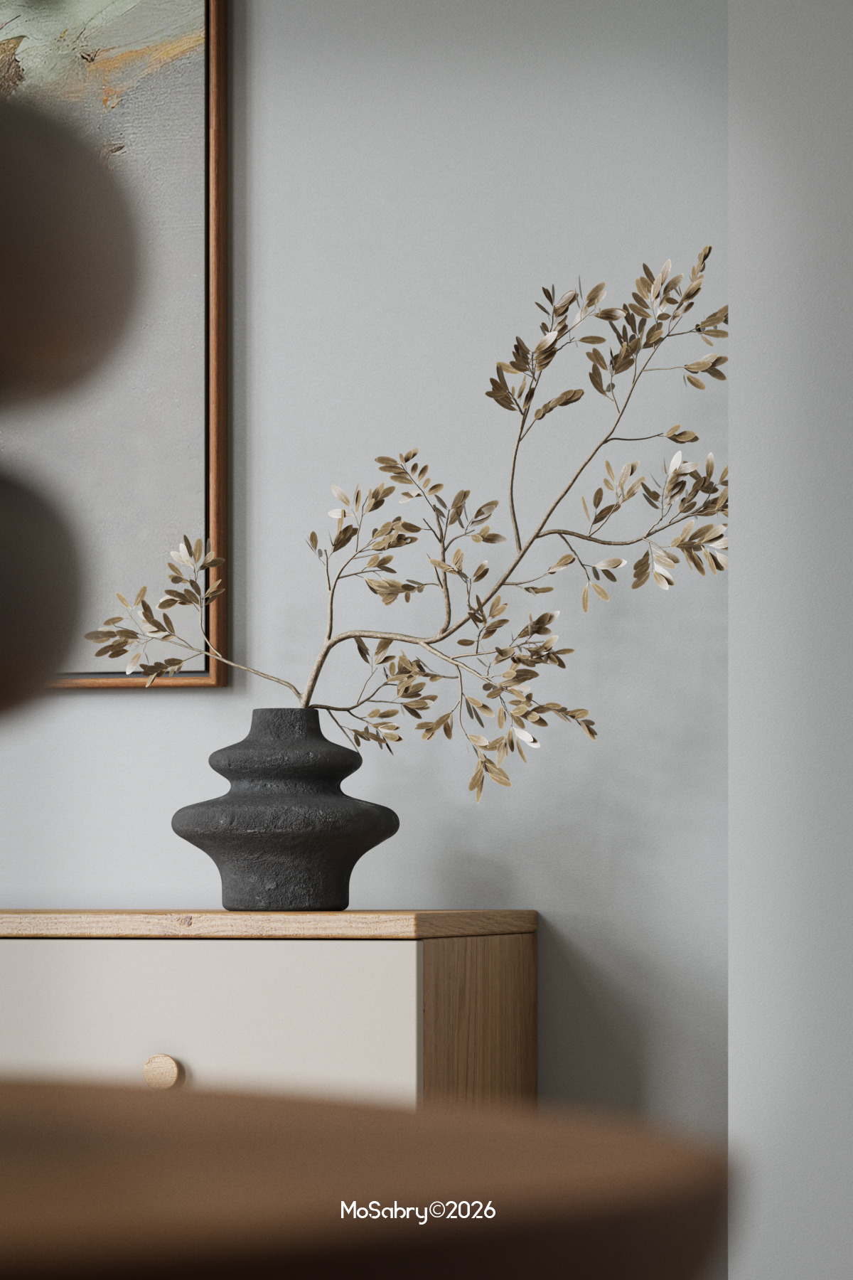 Dried branches in a dark ceramic vase on a wooden cabinet