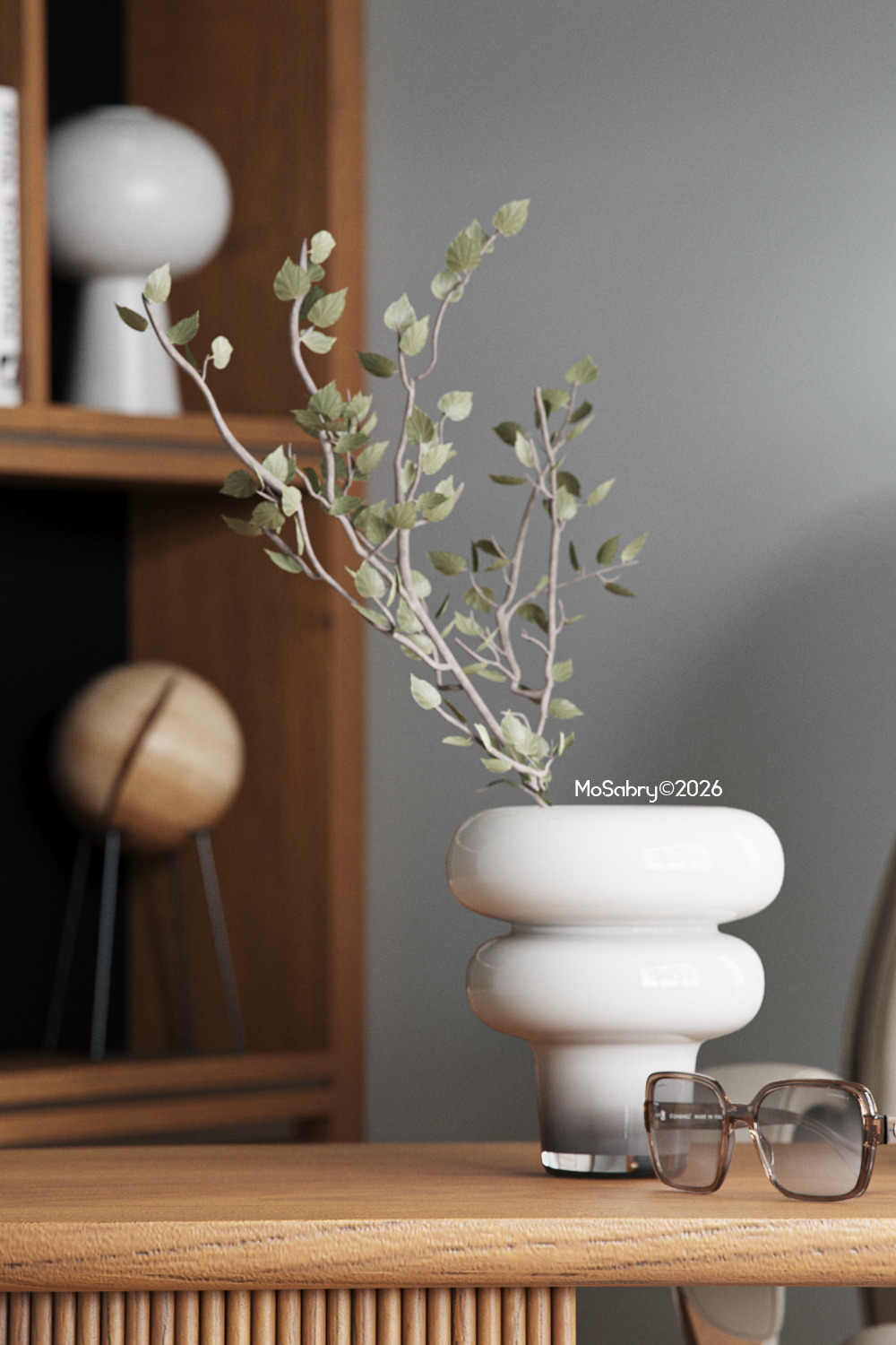 White ceramic vase with leafy branches and a pair of glasses on a wooden table