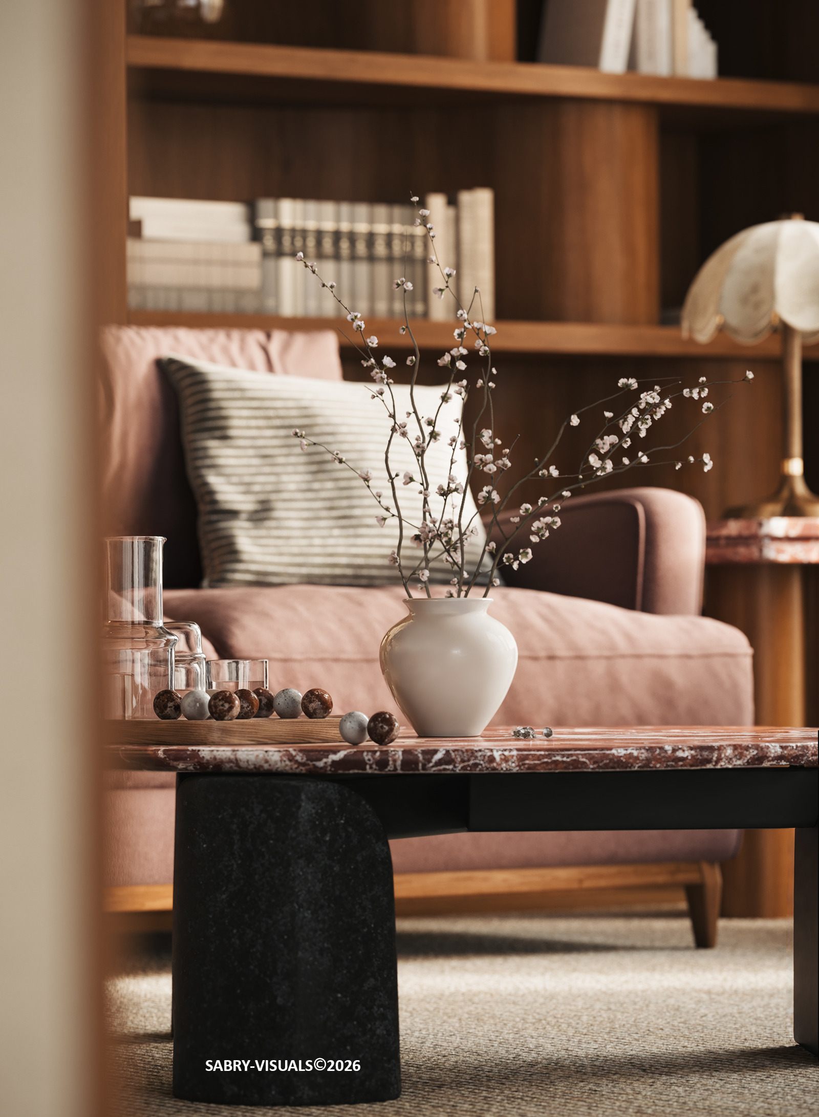 Ceramic vase with blossom branches on a marble coffee table in front of a pink sofa